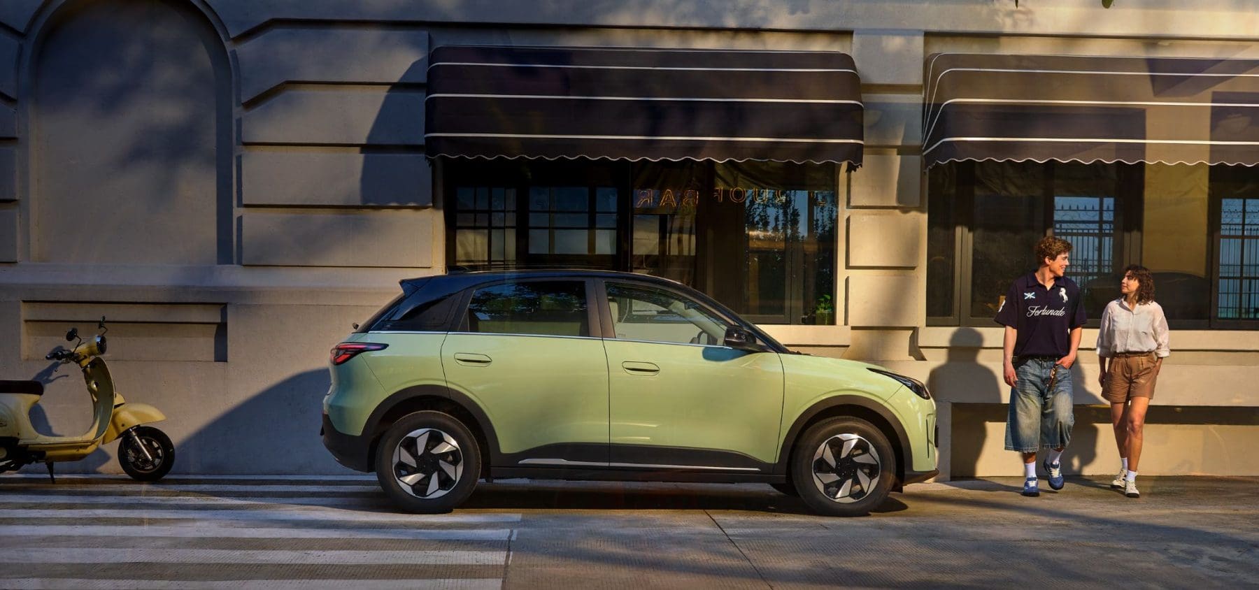 Geely E2 w kolorze zielonym zaparkowane przy miejskiej kamienicy
