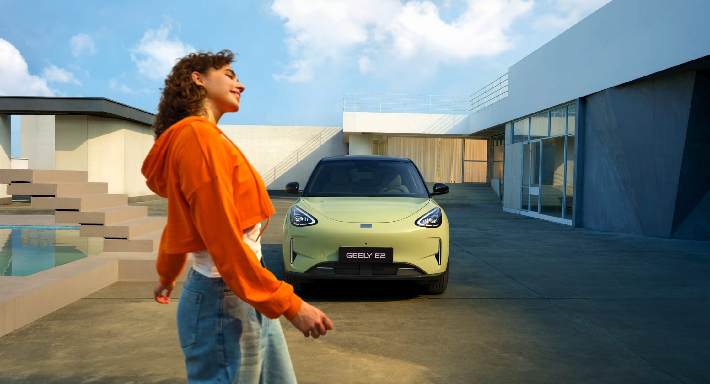 Zielone Geely E2 zaparkowane przed nowoczesnym domem
