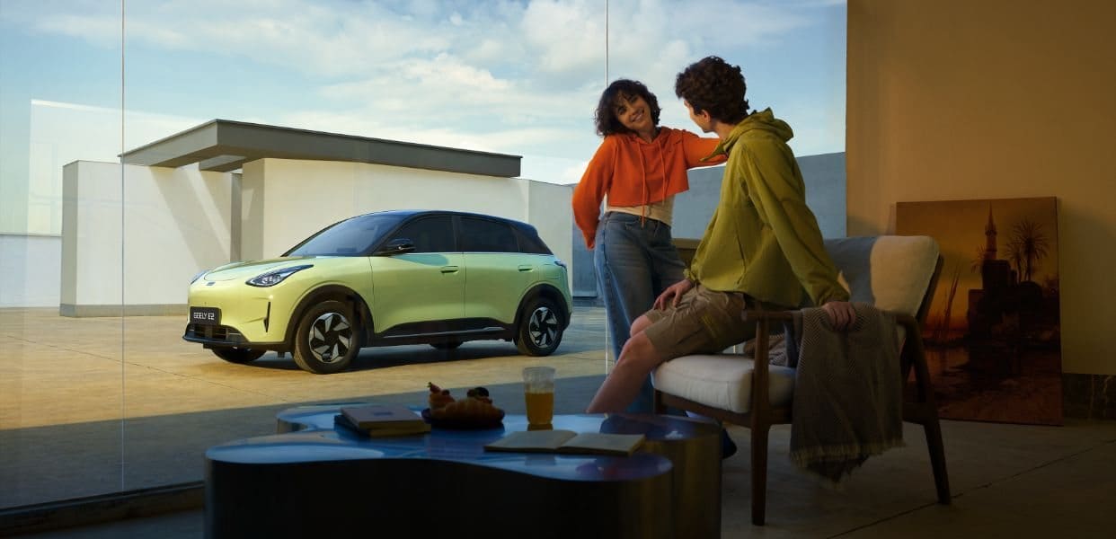 Para odpoczywająca w salonie, w tle zaparkowane Geely E2